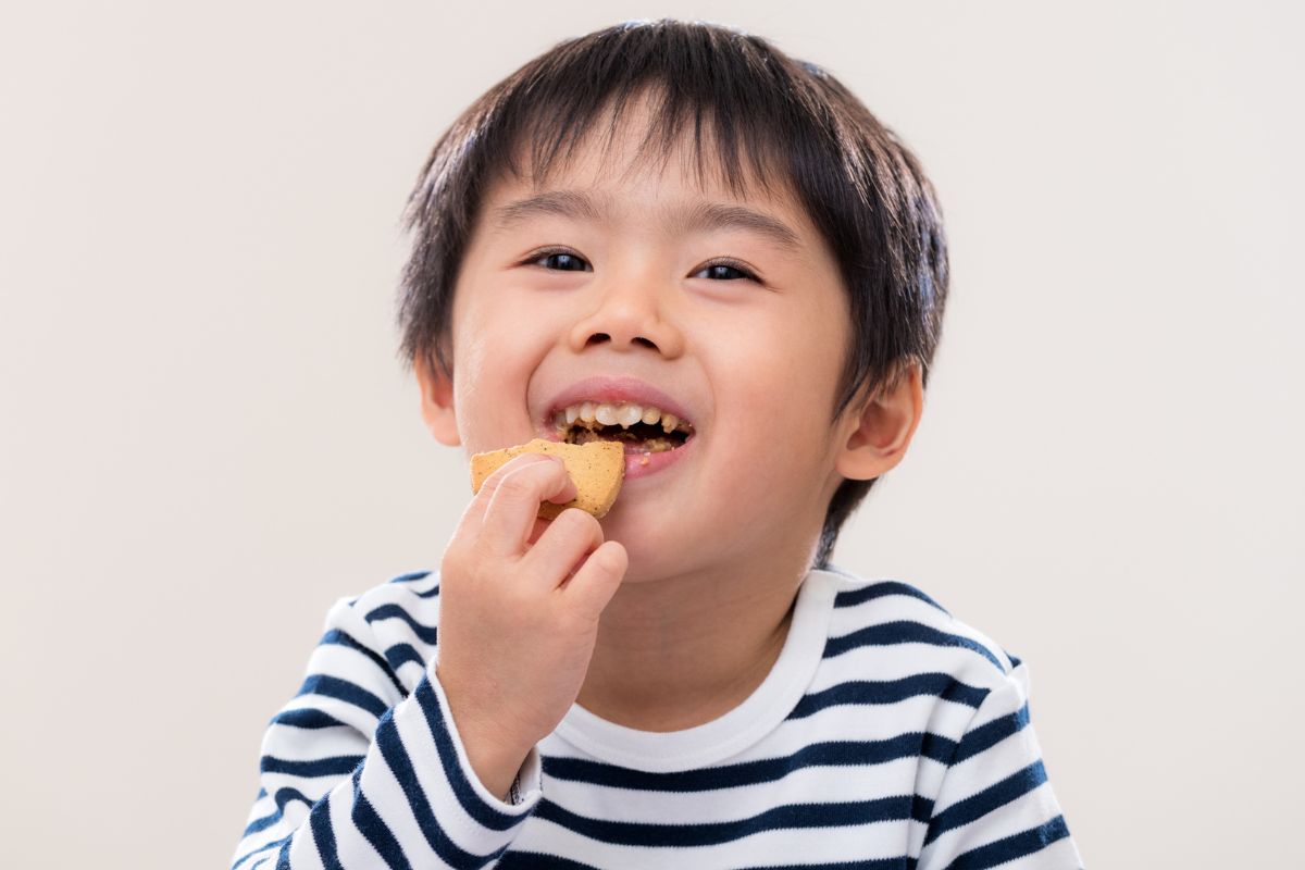 Anak laki-laki sedang makan biskuit