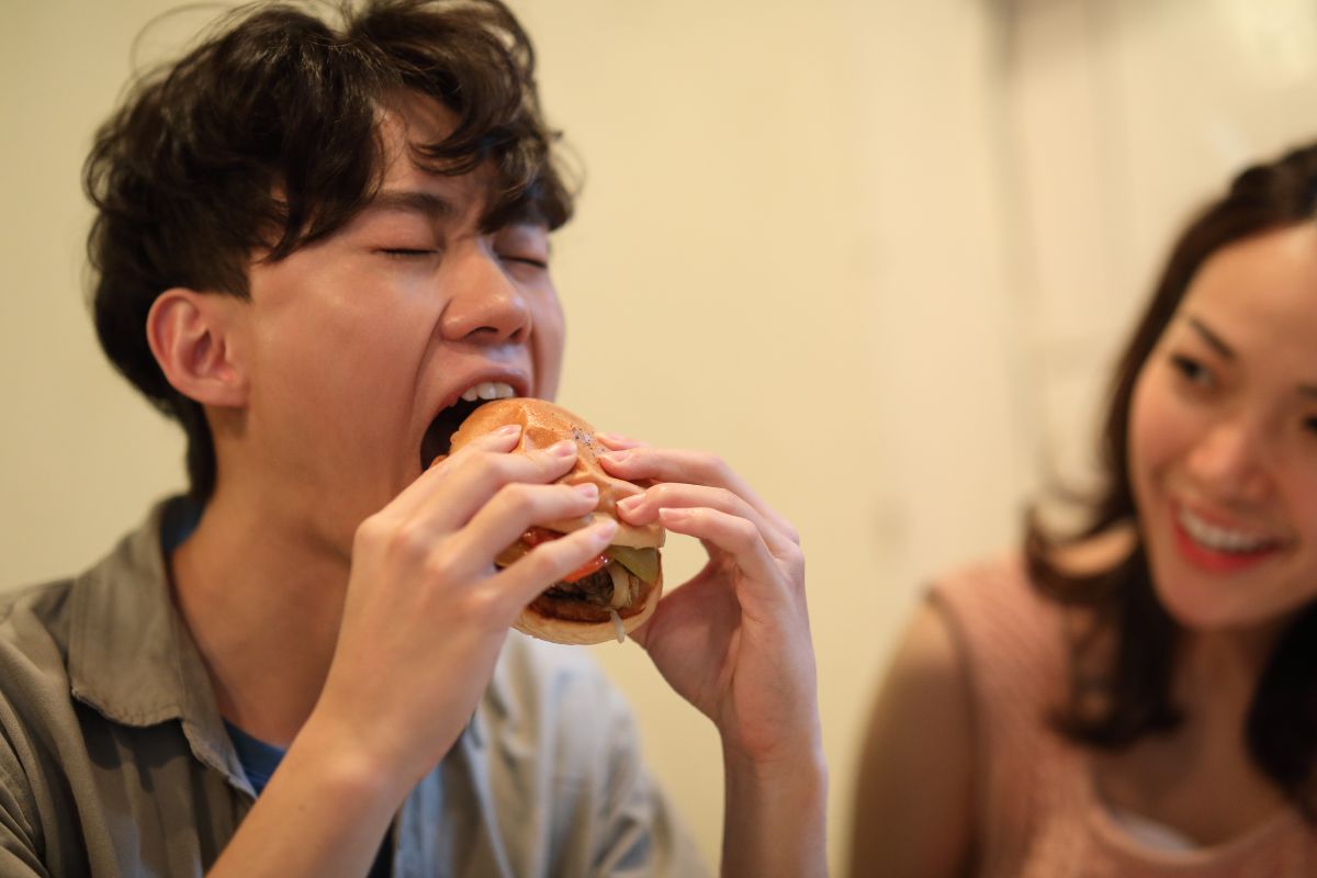Seorang pria sedang menyantap burger