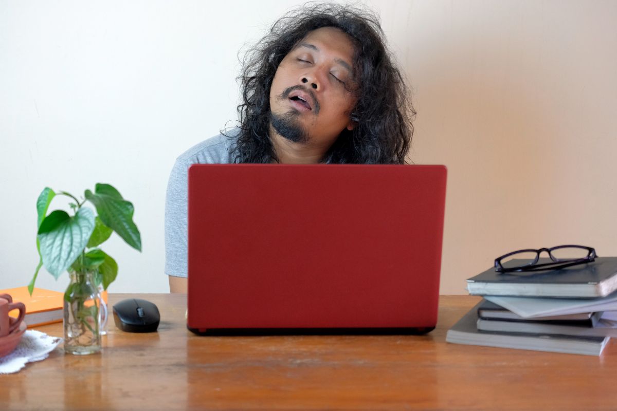 Seorang pria tertidur di depan laptop