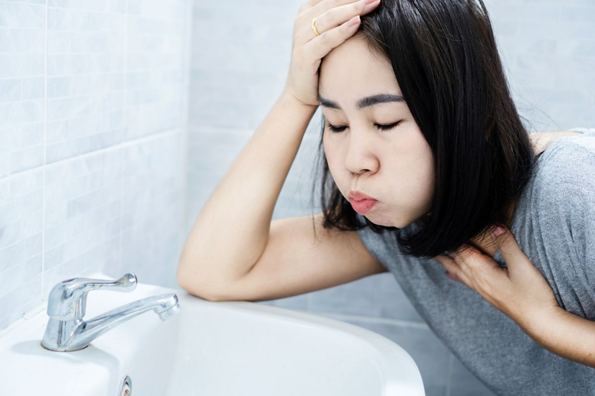 Seorang wanita sedang menahan rasa mual