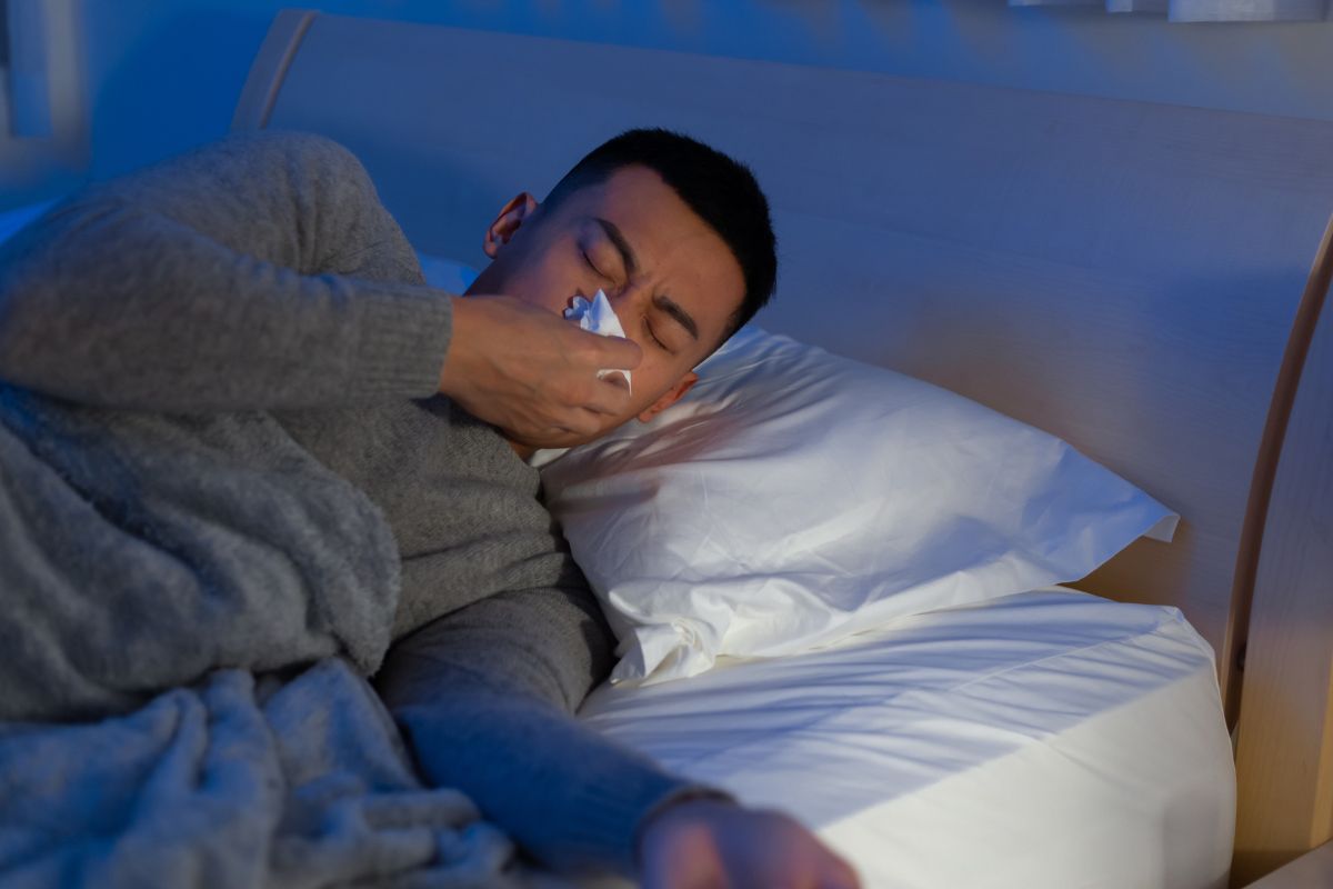 Seorang pria sedang membuang ingus di hidung