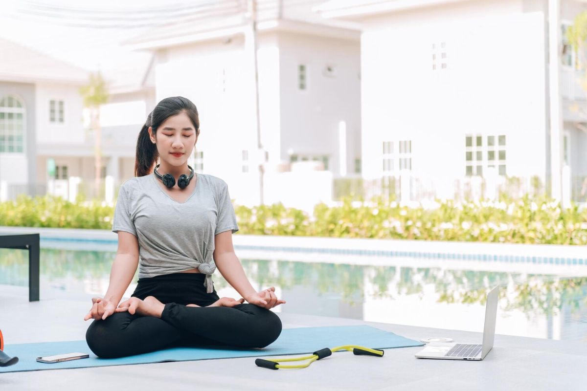 Perempuan sedang yoga di pinggir kolam renang