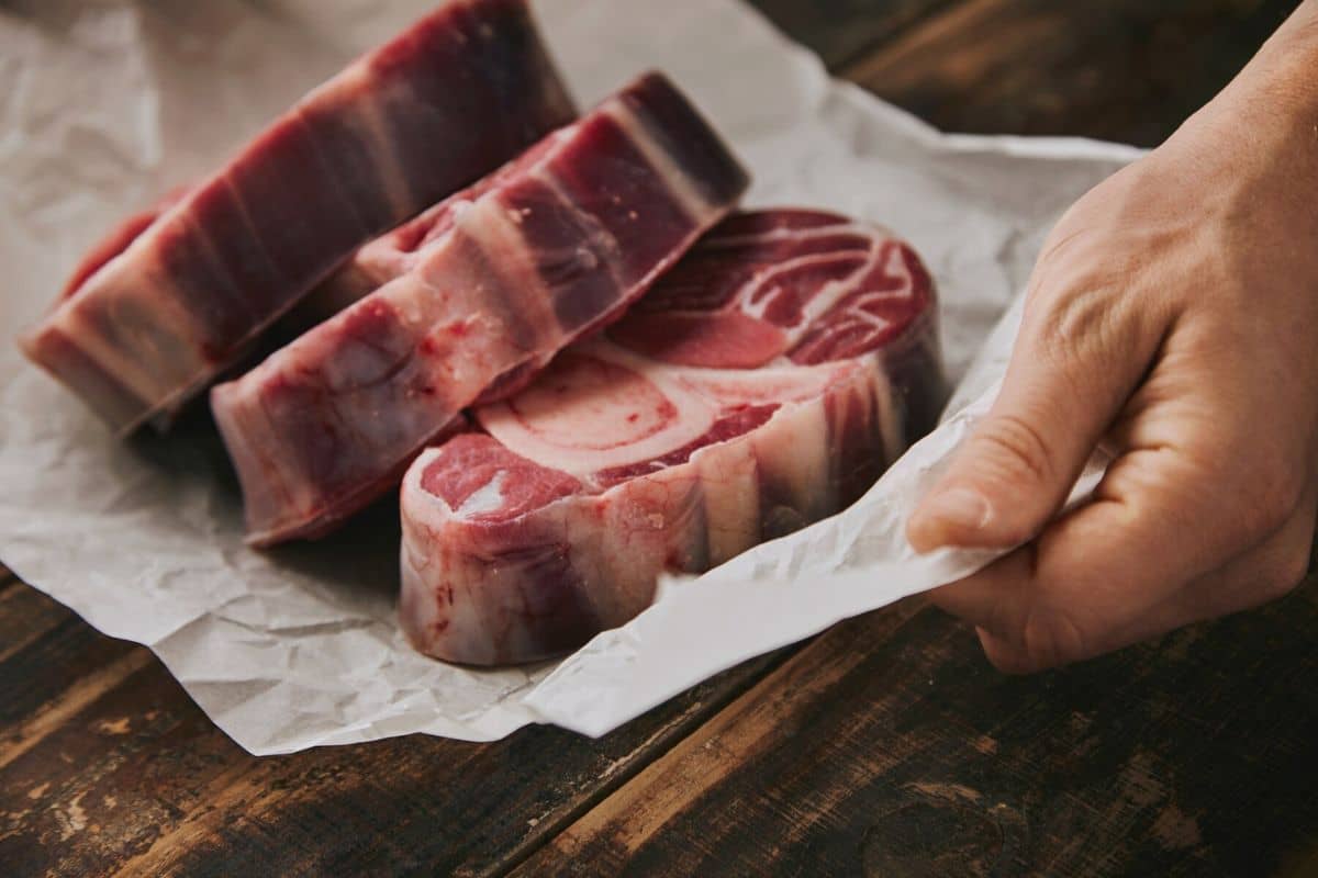 Tangan memegang kertas alas potongan daging sapi