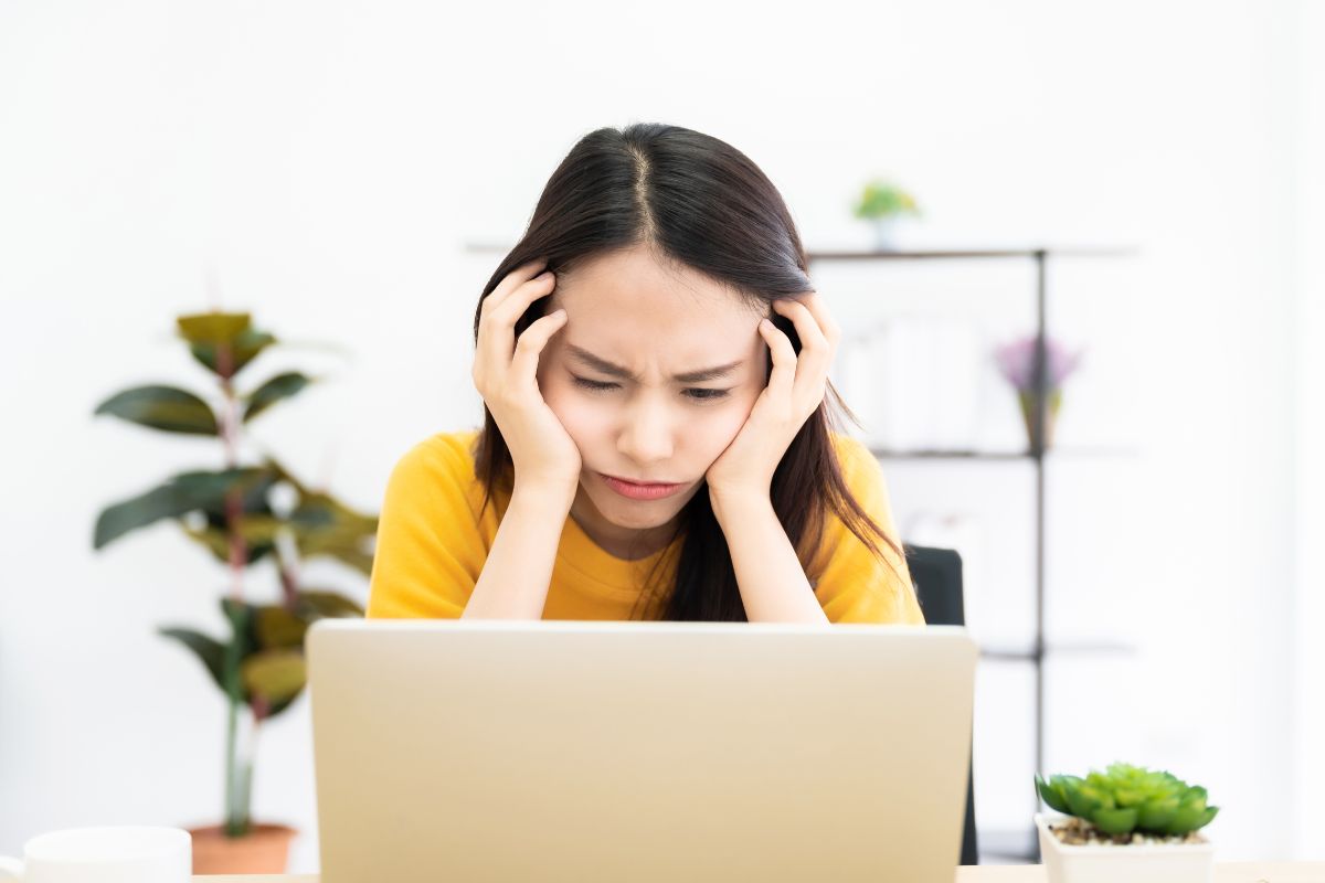 Seorang wanita sedang cemberut di depan layar laptop