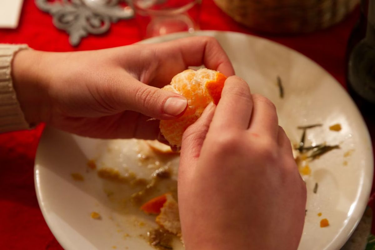 Seseorang mengupas kulit jeruk