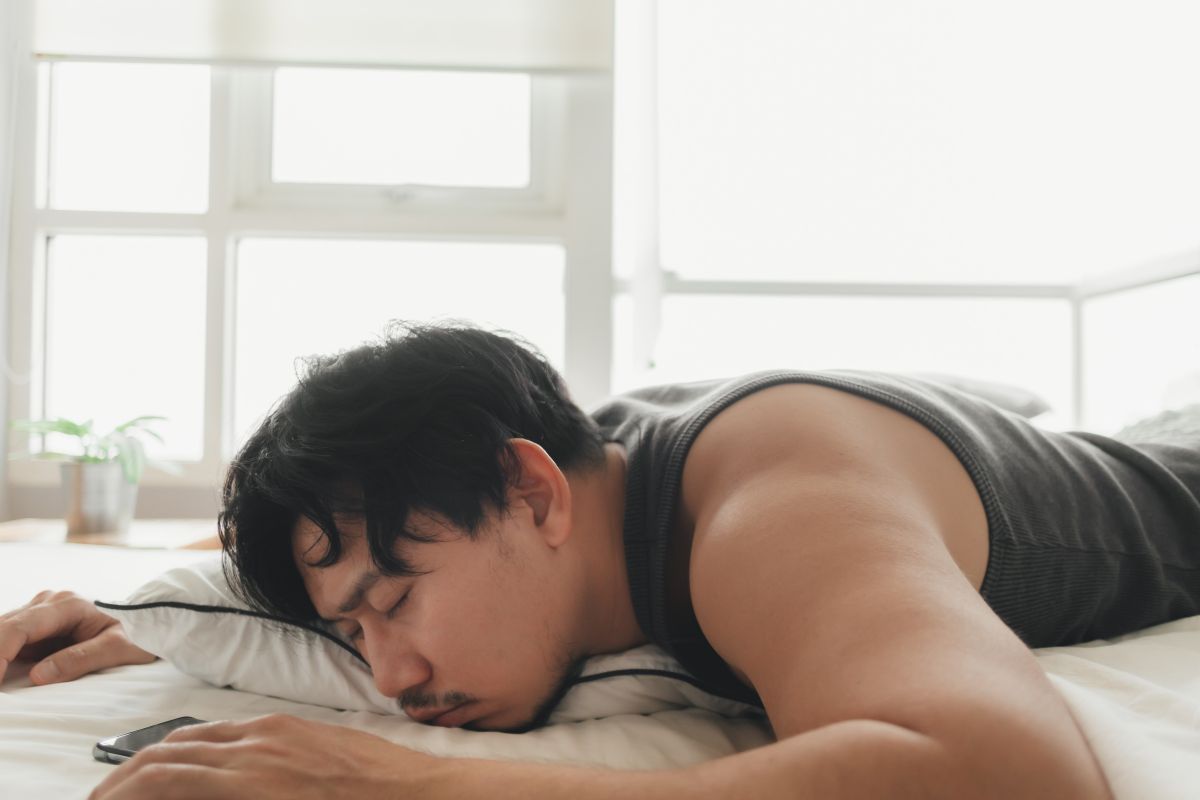 Seorang pria sedang rebahan di atas kasur