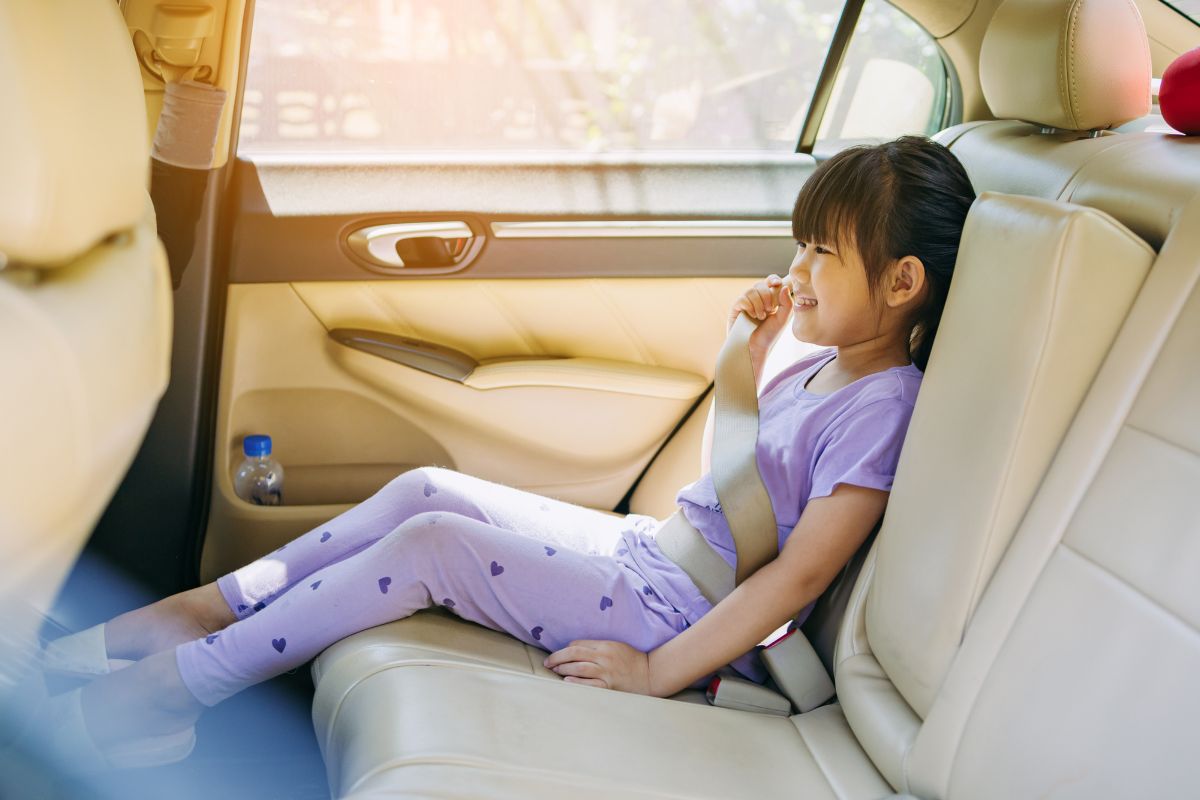 Anak perempuan duduk di kursi belakang mobil