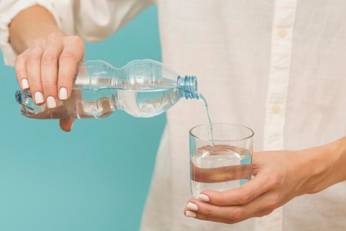 Seorang perempuan sedang menuang air dalam gelas