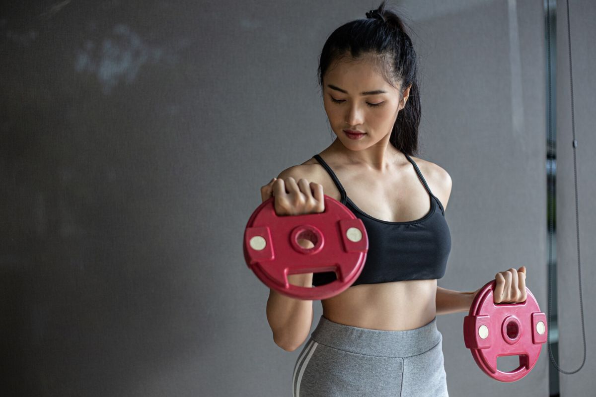 Wanita sedang berolahraga menggunakan dumbbell