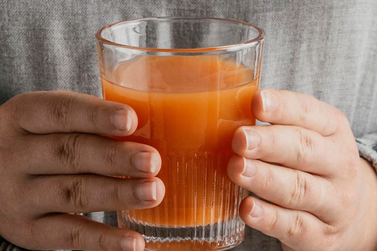 Perempuan memegang segelas jamu