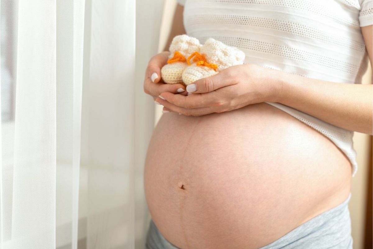 Ibu hamil memegang sepatu bayi