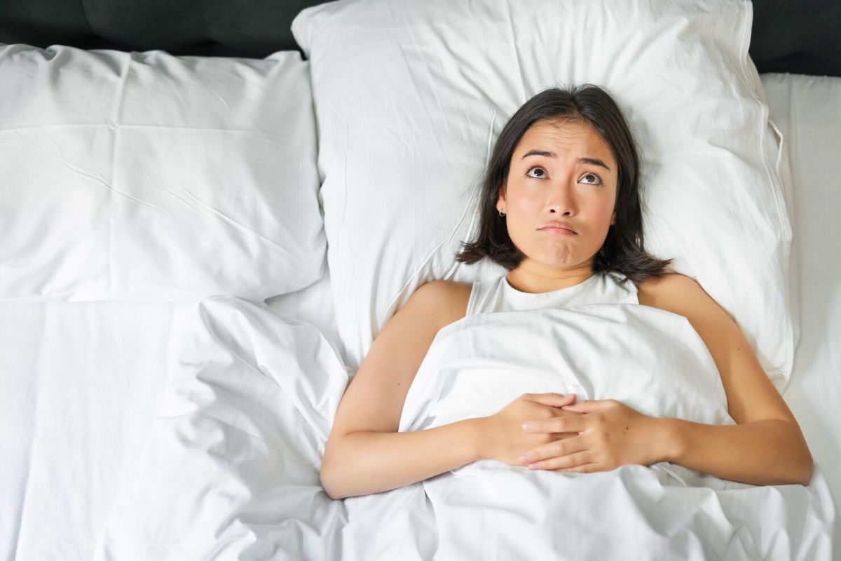 Perempuan tiduran menatap langit-langit kamar