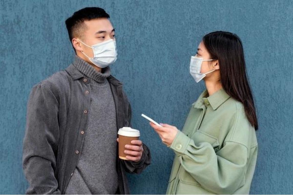 Dua orang berbincang mengenakan masker
