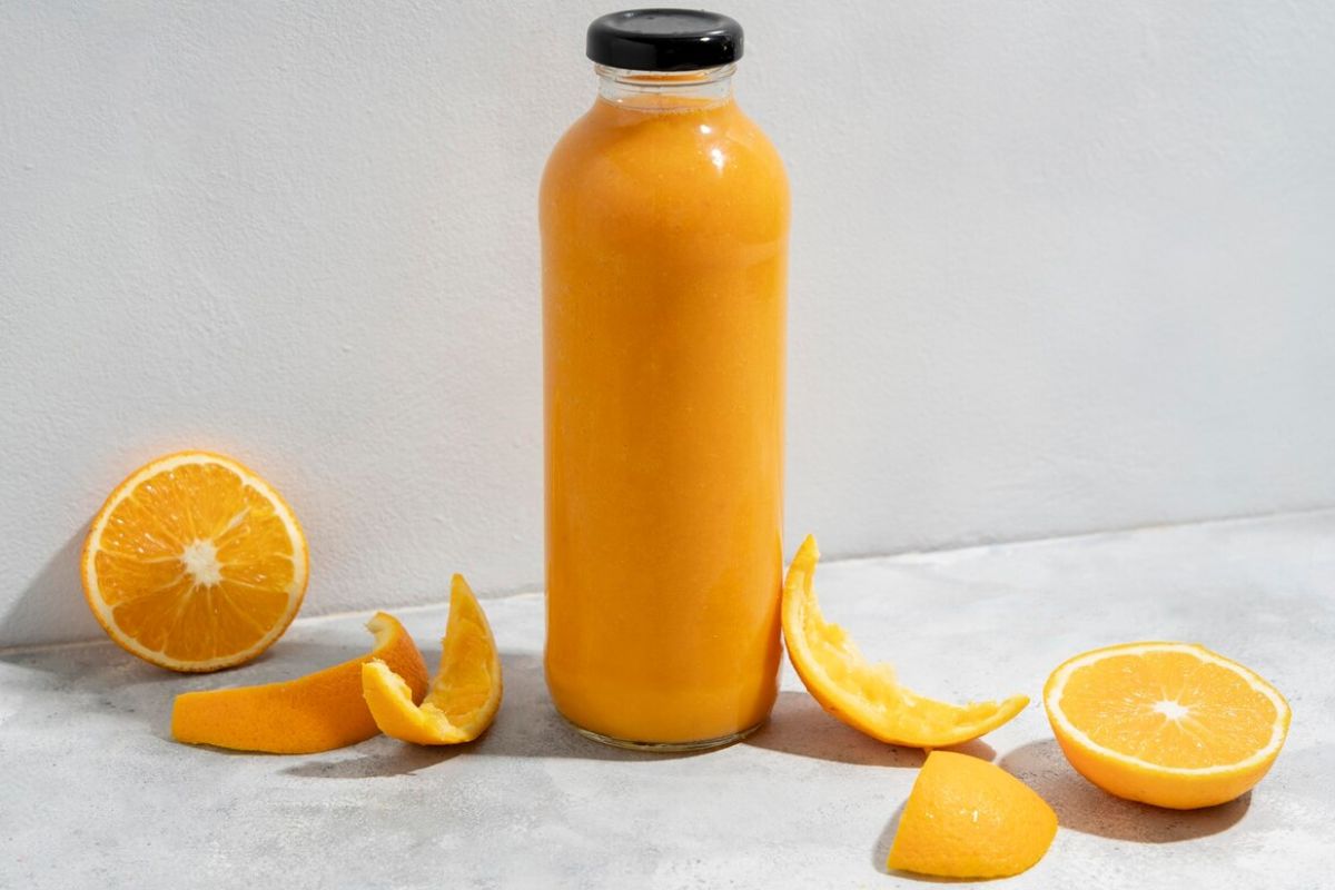 Jus jeruk dalam botol dengan potongan buah jeruk