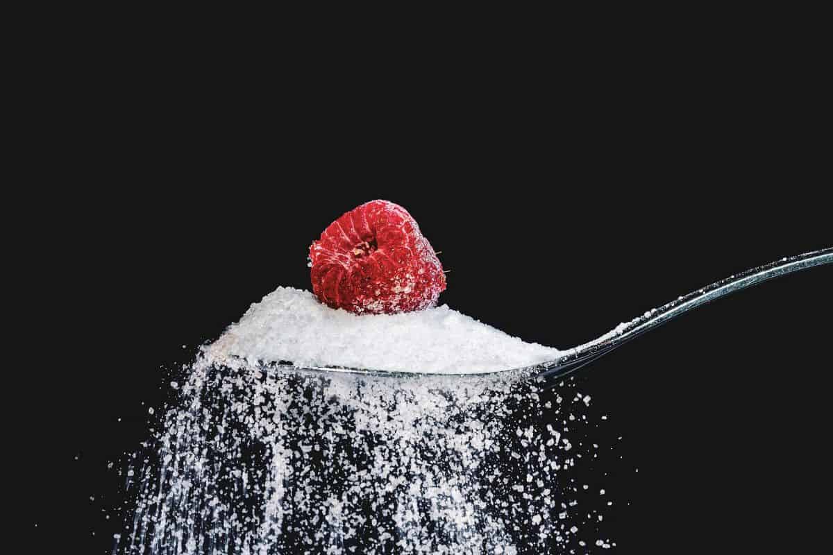 buah raspberry di atas sesendok gula