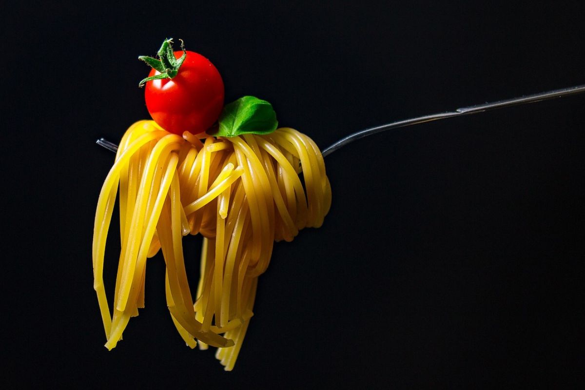 orang yang mengambil satu suap pasta dan tomat
