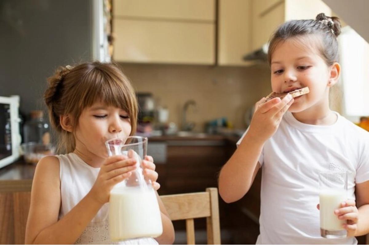 Dua anak perempuan sarapan dengan susu