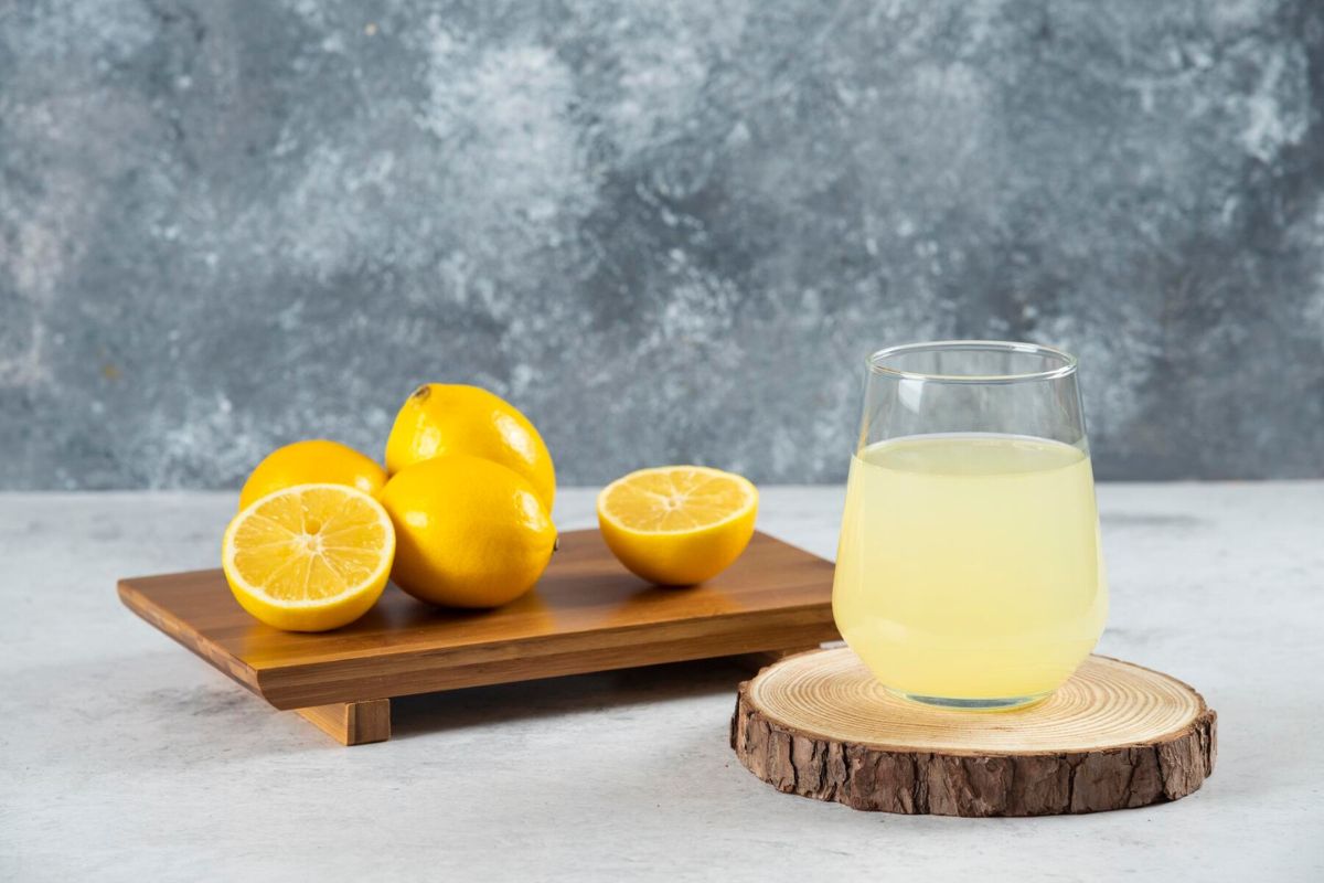 Segelas jus lemon dan potongan buah lemon di atas nampan