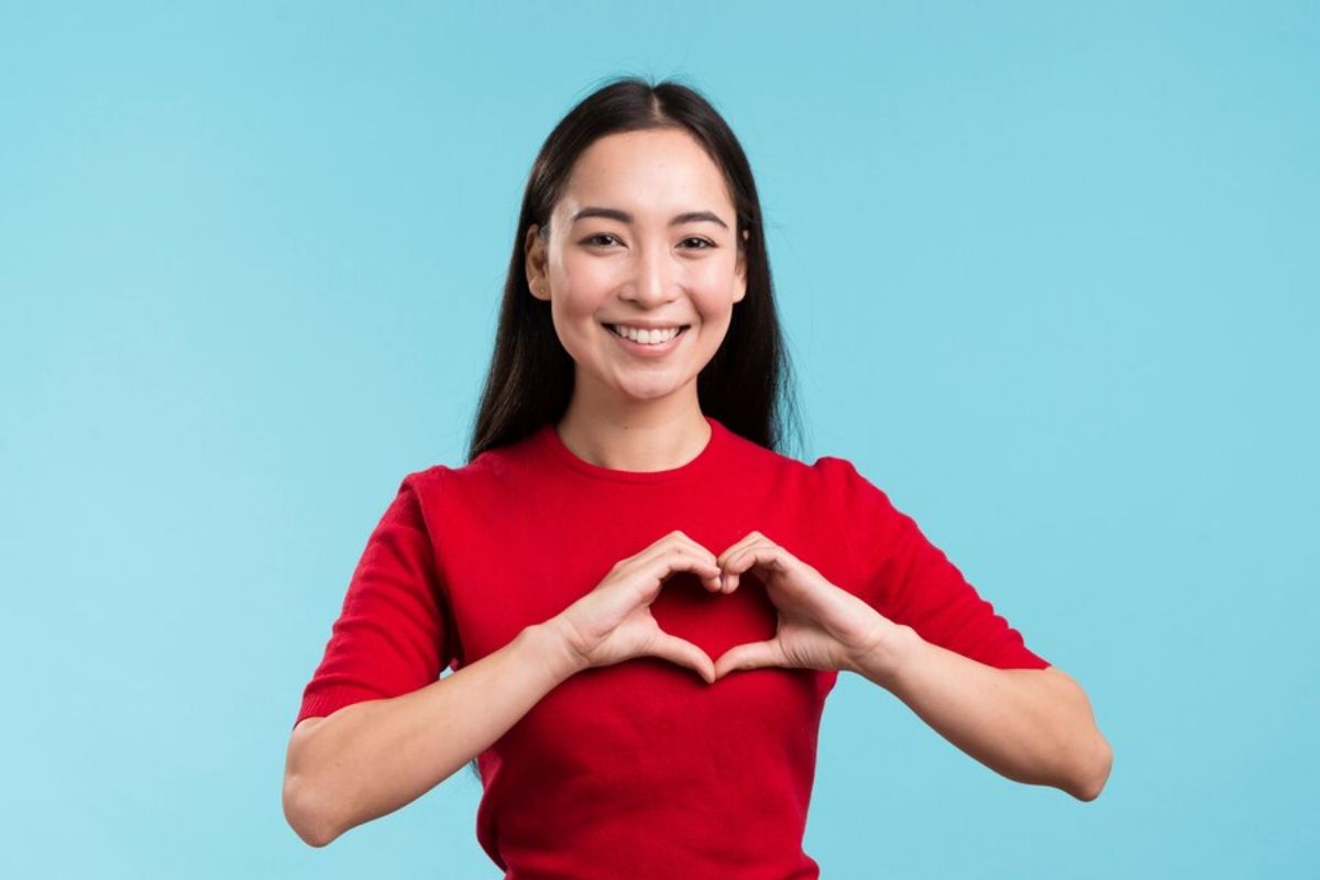 Perempuan berkaos merah menunjukkan jantungnya