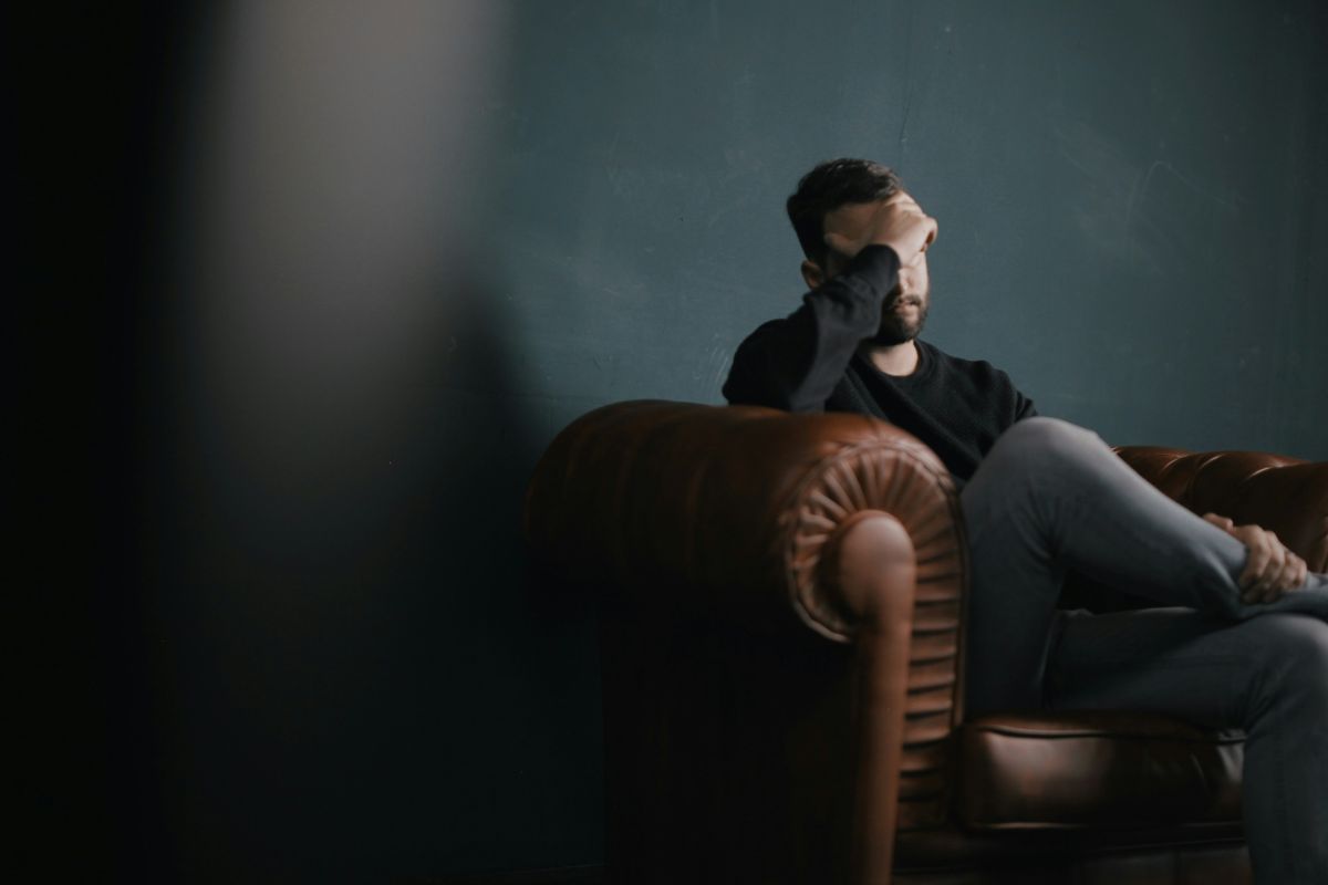 orang yang memegang kepala sambil terduduk di sofa