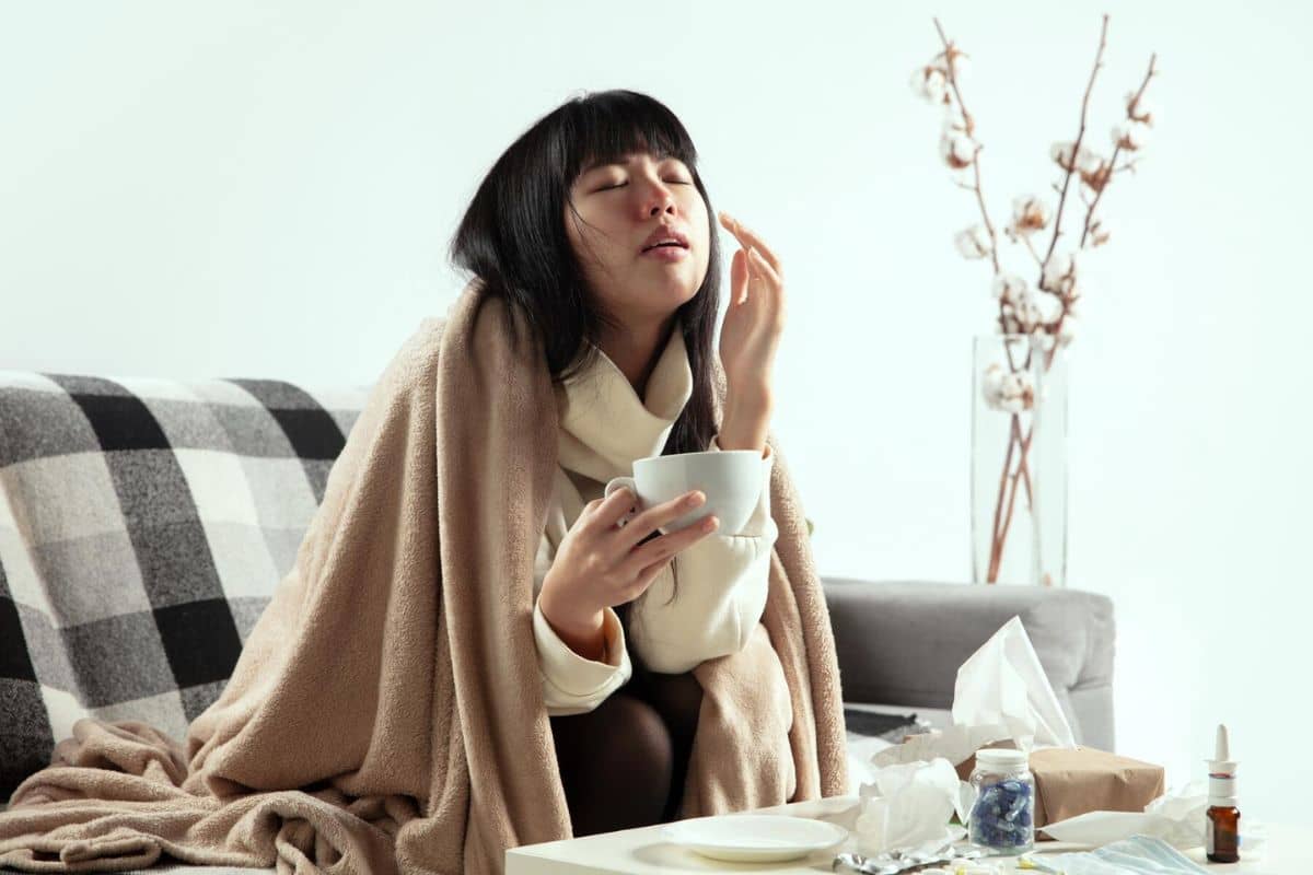 Wanita sedang meminum minuman hangat untuk atasi hidung tersumbat