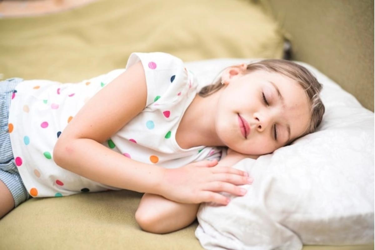 Anak perempuan memejamkan mata di atas kasur nyaman