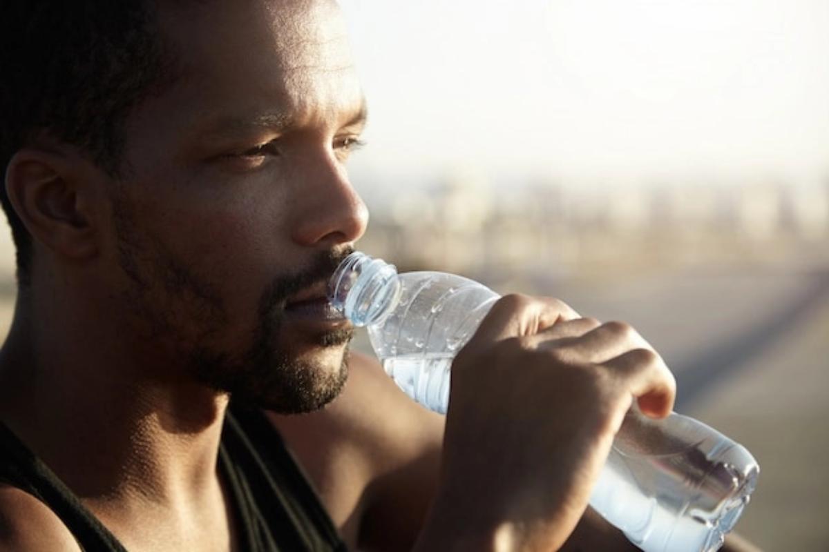 Laki-laki minum air putih dari botol