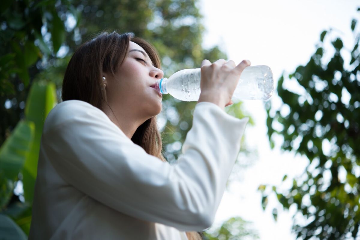 Perempuan minum air dingin dari botol