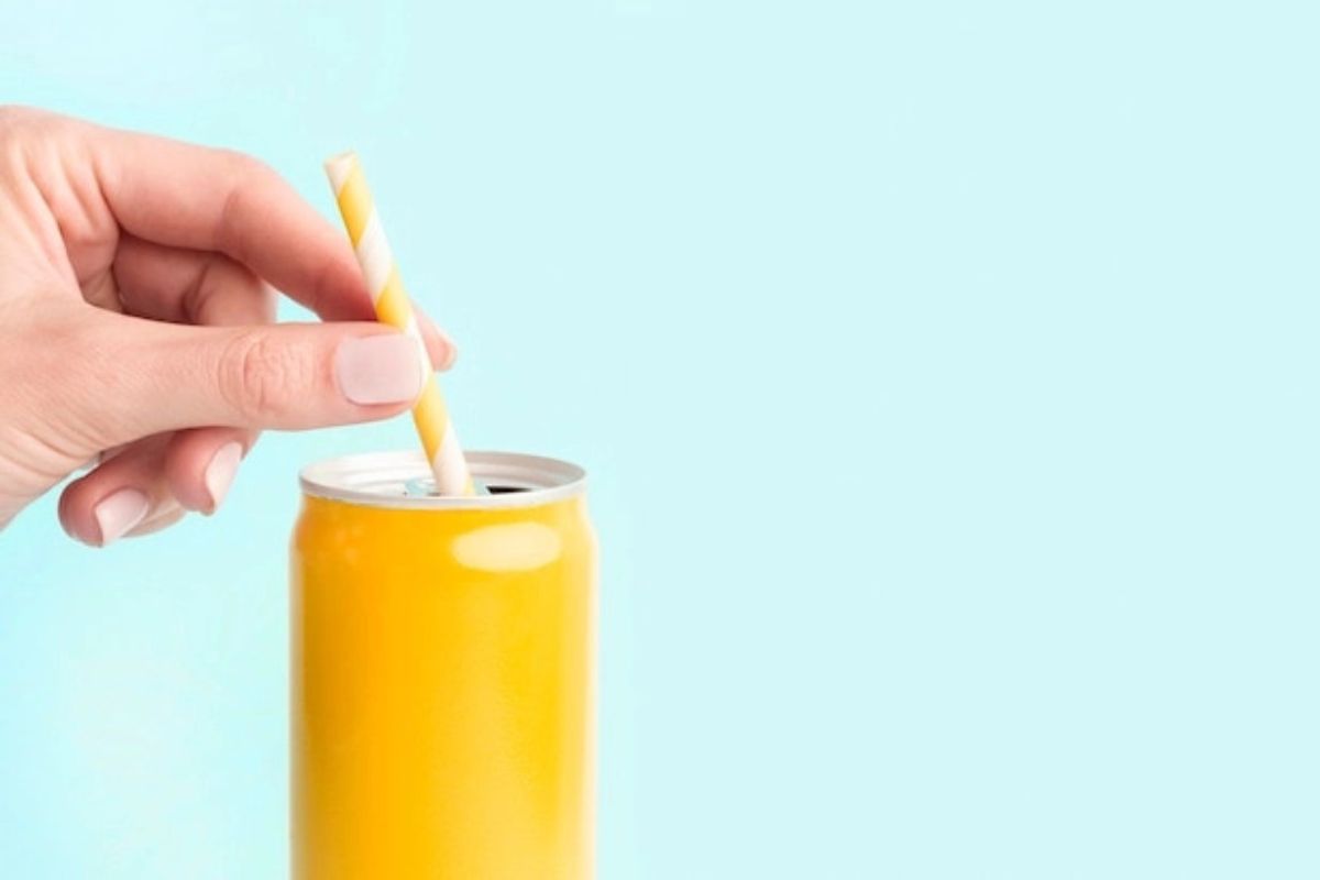 Tangan memegang sedotan di dalam minuman kaleng