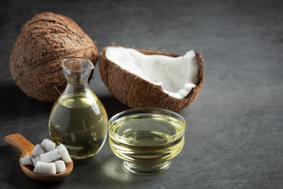 Minyak kelapa dalam botol kaca dan mangkuk kaca