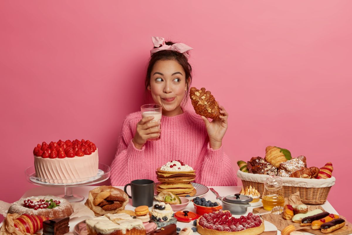 orang yang duduk di depan meja penuh makanan manis