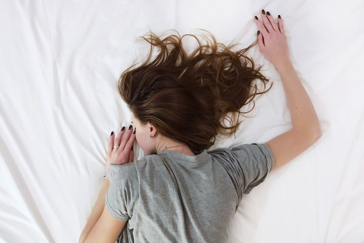 Perempuan tengkurap di kasur putih