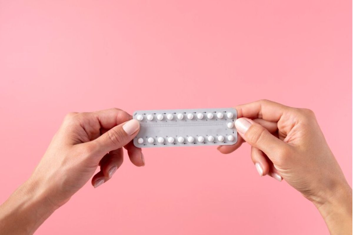 Tangan seorang perempuan memegang satu papan pil