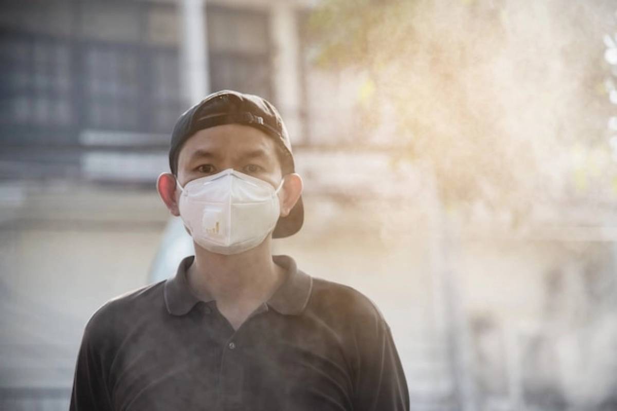 orang yang sedang melindungi diri dari sinar UV dan polusi dengan masker dan topi