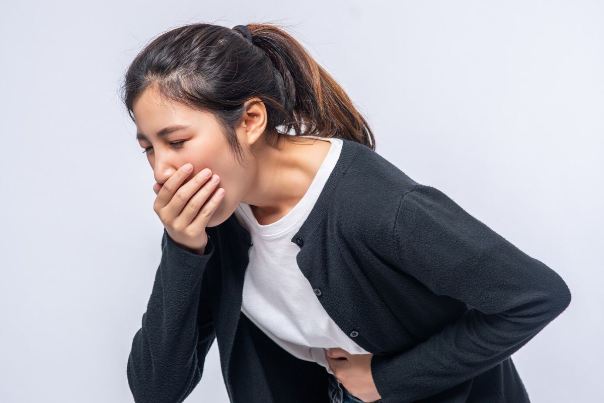 Wanita sedang menutup mulut dan memegangi perut