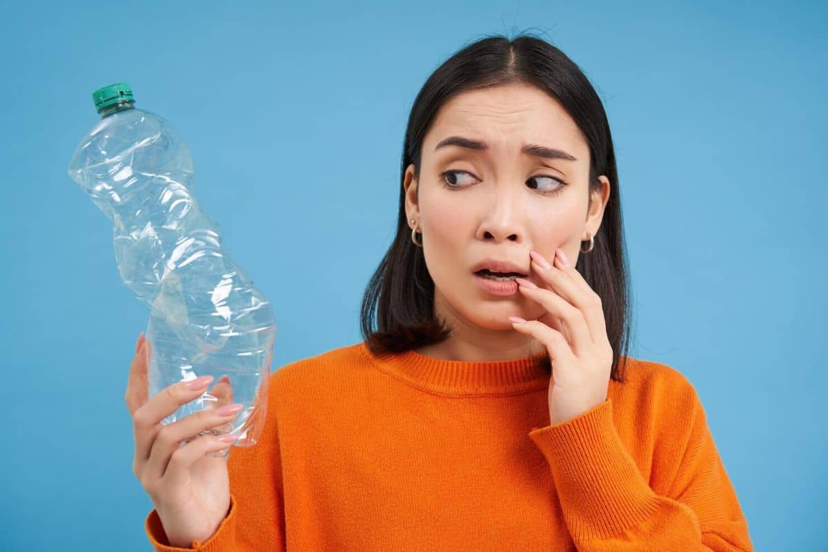 Perempuan menatap botol plastik yang kosong