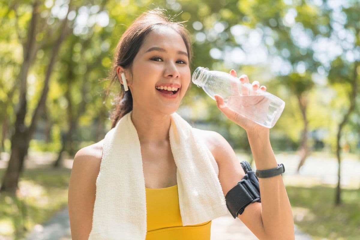 Perempuan mengangkat botol air setelah jogging