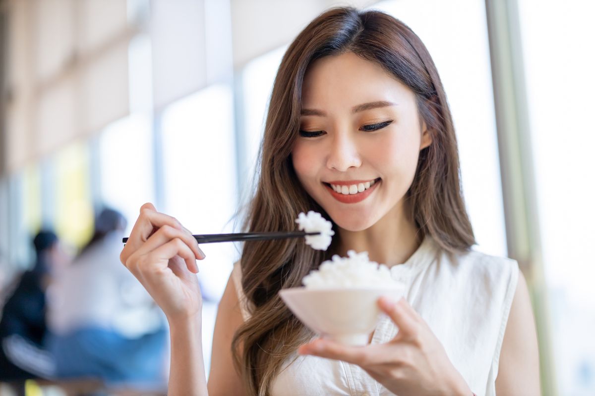 Seorang wanita sedang memakan nasi putih